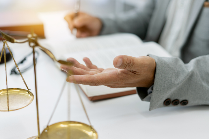 legal consultant advises client on a lawsuit, discussing plans and rights while focusing on honesty and integrity, with legal books and scales at hand in a professional setting.