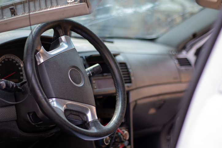 Close-up of the steering wheel of a car after an accident. The driver's airbags did not deploy. Soft focus. Broken windshield with steering wheel. Vehicle interior. Black dashboard and steering wheel