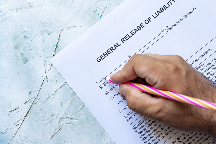 Person filling General Release of Liability form paper on bright background