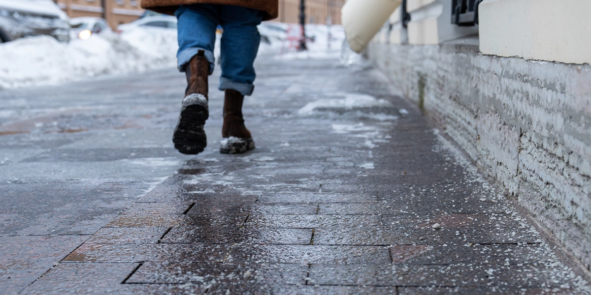 Icy sidewalk in New York covered in snow during winter storm creating dangerous slip and fall conditions
